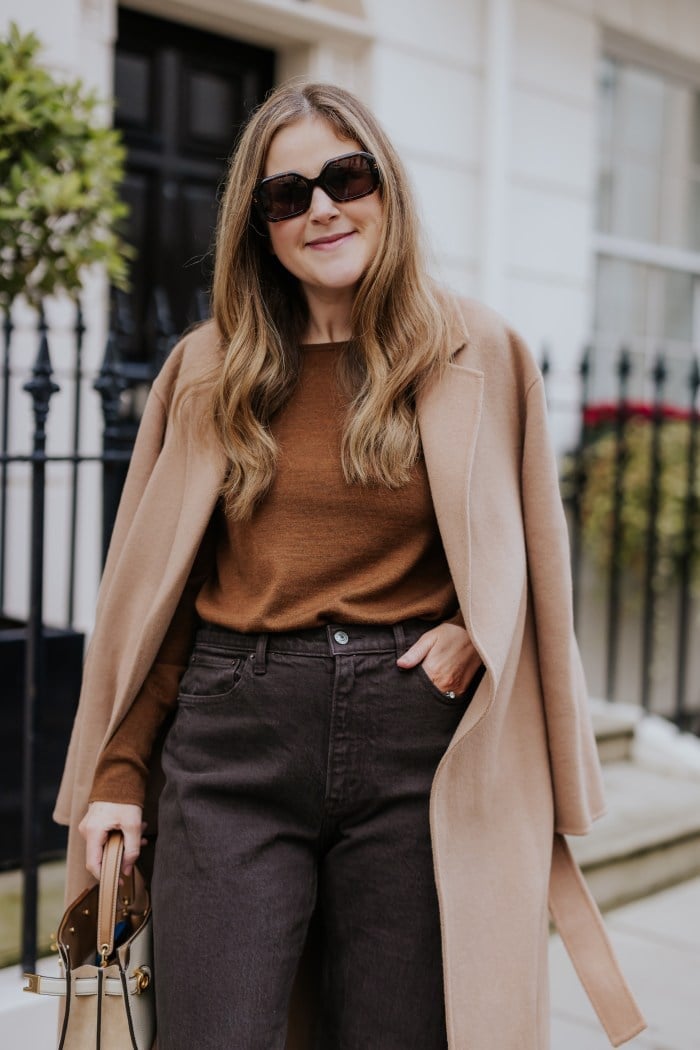 Camel Coat Draped Over Brown Sweater And Gray Jeans Camel Coat Draped Over Brown Sweater And Gray Jeans — Classy London Outfits