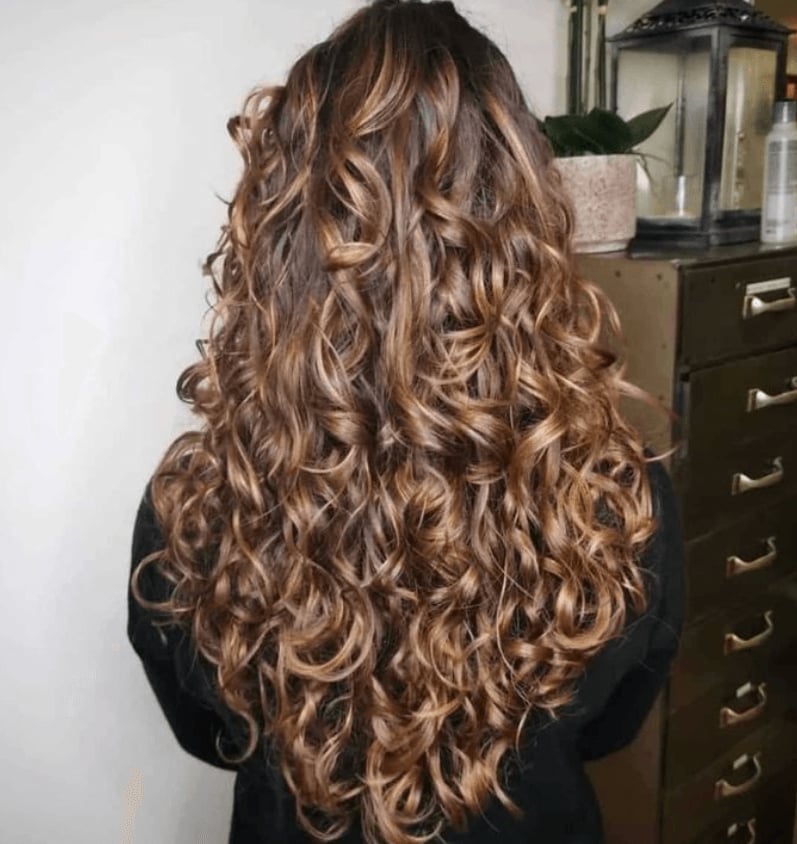Mid-Back Dark Brown With Blonde Highlights — Trendy Brown Curly Hair