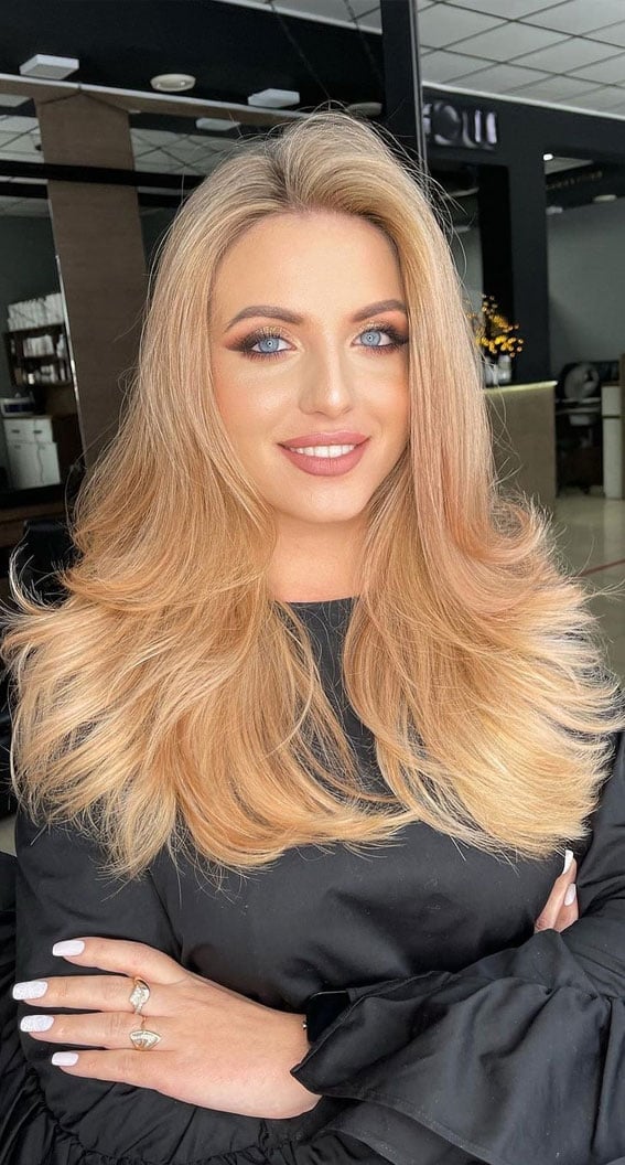 Mid-Back Apricot Blonde With Curtain Bangs and Showcasing A Thick — Trendy Light Hair Color