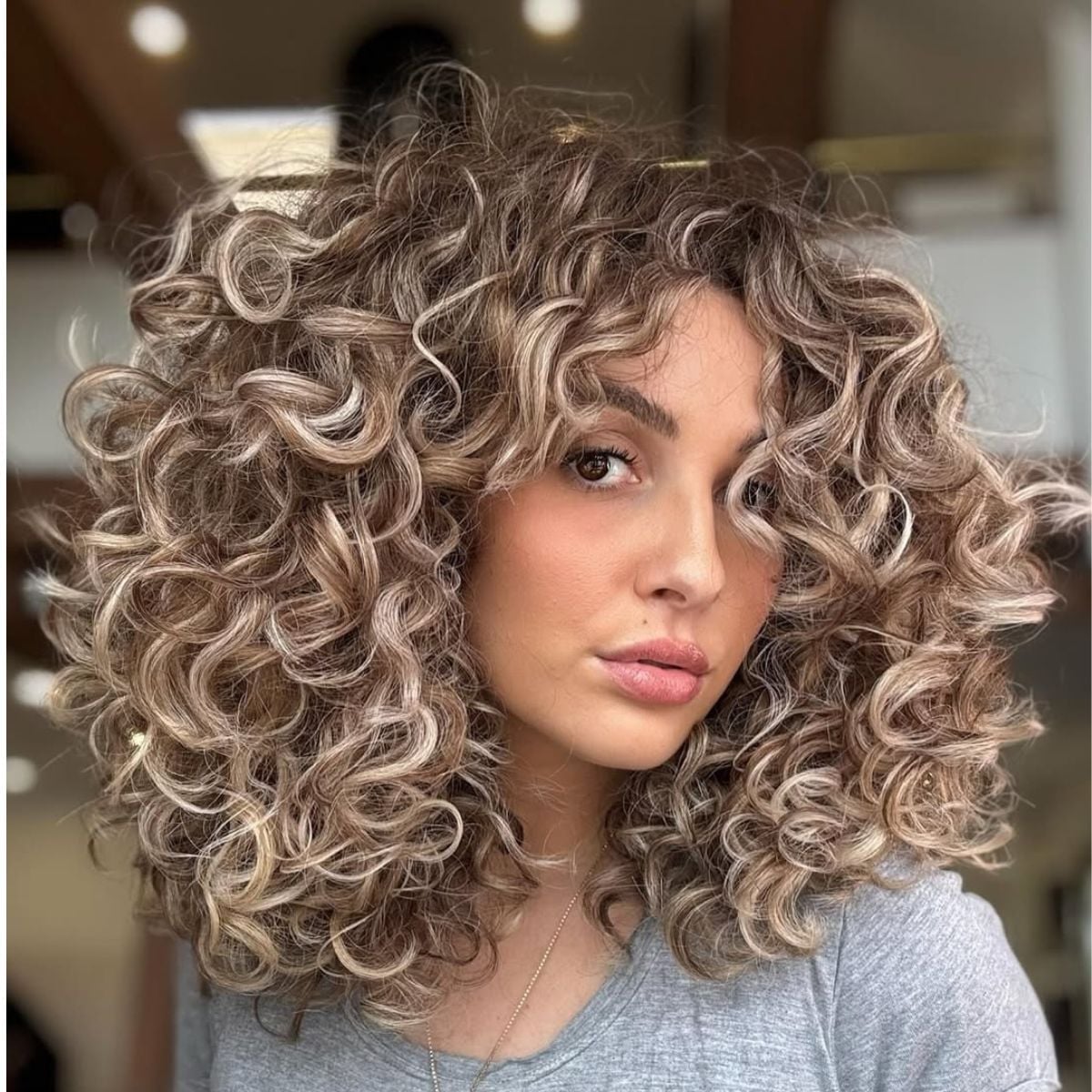 Voluminous Collarbone Cut With Balayage And Curtain Bangs Voluminous Collarbone Cut With Balayage And Curtain Bangs — Trendy Medium Curly Hair