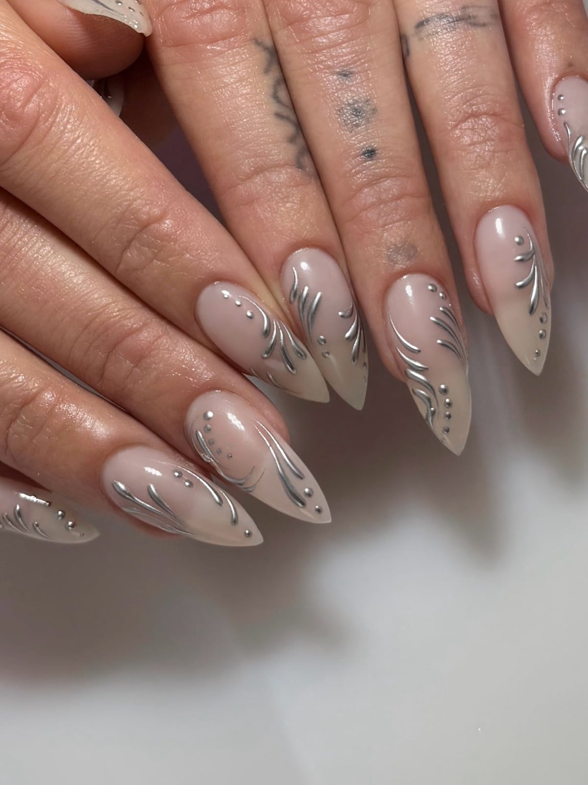 Long Stiletto Nails With Sheer Nude and Silver Swirls Long Stiletto Nails With Sheer Nude and Silver Swirls — Trendy Silver Chrome Nails