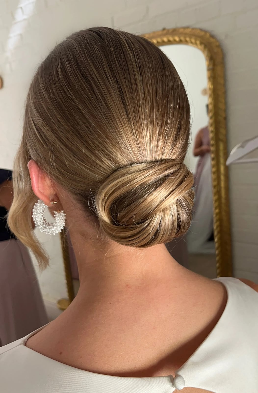 Polished Blonde Updo With Soft Tendrils — Trendy Wedding Guest Updos