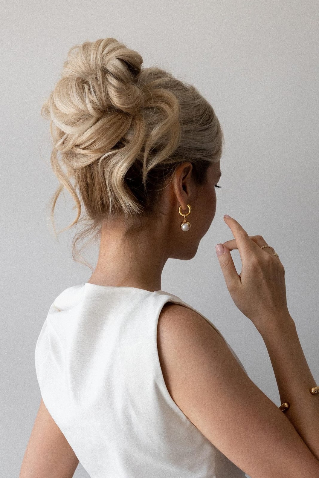 Voluminous Blonde High Bun With Curls — Trendy Wedding Guest Updos