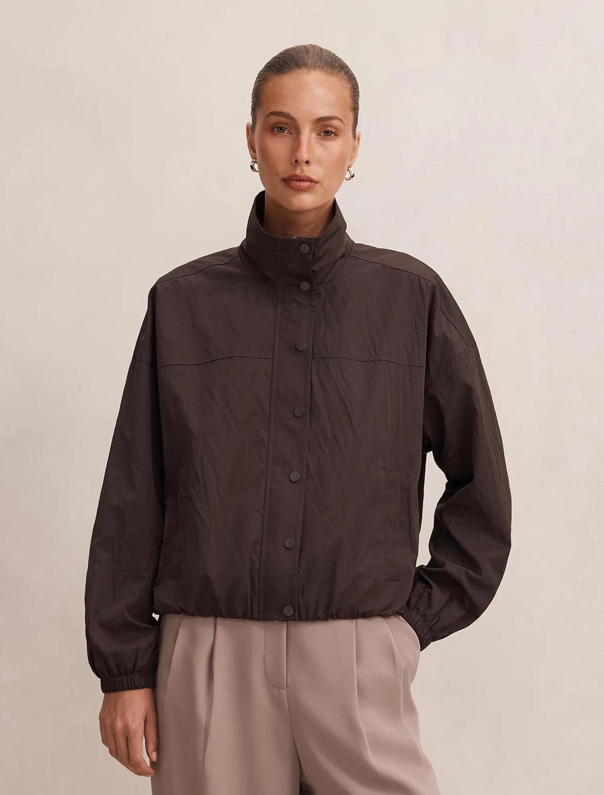 Dark Brown Cropped Windbreaker with Beige Trousers, Close-Up Take — Trendy Windbreaker Outfits