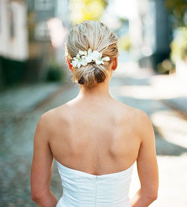 Low Textured Blonde Bun With Floral Accessory Low Textured Blonde Bun With Floral Accessory — Wedding Bun Ideas